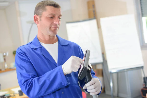 Trabajador limpiando una aspiradora — Foto de Stock