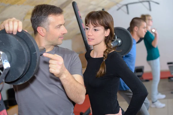 Entraîneur expliquant comment utiliser une machine d'entraînement dans un gymnase — Photo