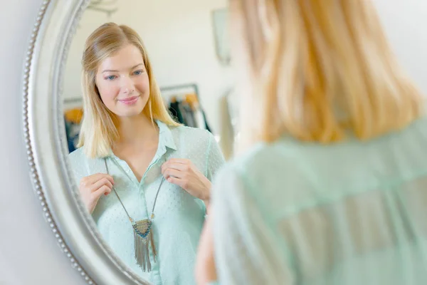 Lady se snaží na náhrdelník před zrcadlem — Stock fotografie