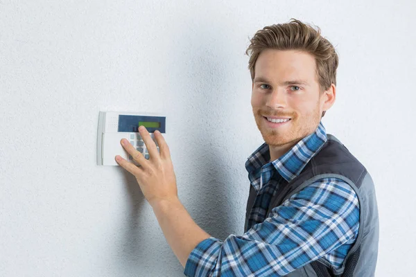 Attractive young handyman checks the security alarm — Stock Photo, Image