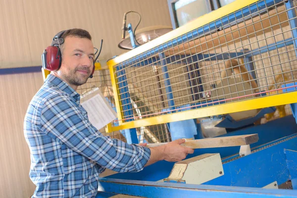 Mann arbeitet hinter Schirm mit Holz — Stockfoto