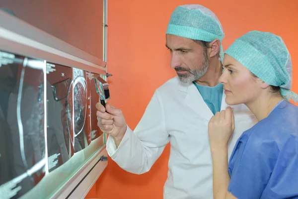 Доктор дивиться на рентгенівський знімок зі збільшувальним склом — стокове фото