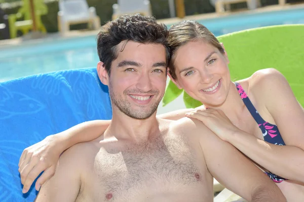 Casal de banhos de sol ao lado da piscina — Fotografia de Stock