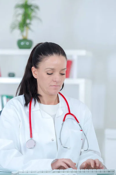 Läkare bär uniform medan du arbetar på skrivbord — Stockfoto