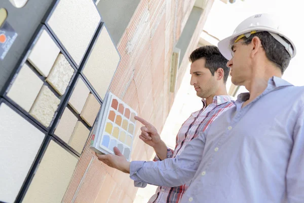 Twee mannen bijpassende kleurstalen op buitenmuur — Stockfoto