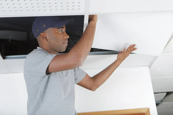 Uomo che sostituisce pannello in controsoffitto — Foto Stock