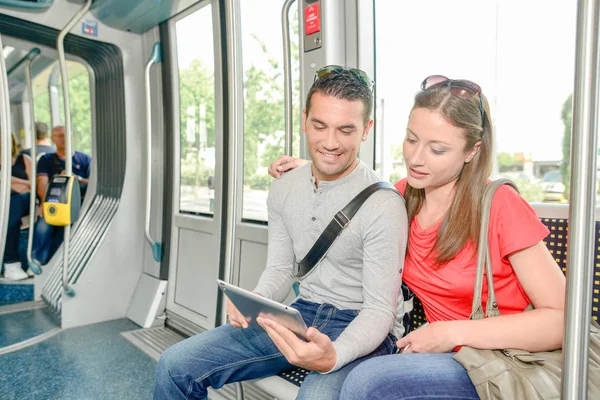 Para przy użyciu komputera typu tablet podczas podróży tramwajem — Zdjęcie stockowe