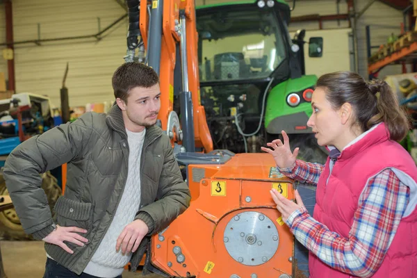 Atraktivní žena prodávat zbrusu nový traktor pro začátečníky farmáře — Stock fotografie