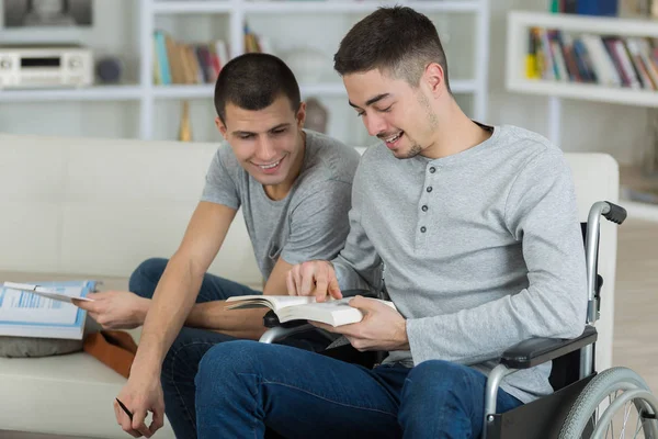 Twee jonge mannen (één uitgeschakeld) op zoek naar een boek — Stockfoto