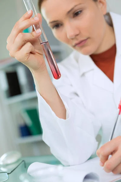 Close-up of female scientist in overall holding tube — Stock Photo, Image