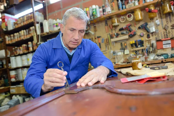 Older man restoring a table — Stock Photo, Image