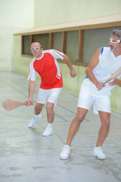 Homens jogando esporte com raquete de madeira — Fotografia de Stock