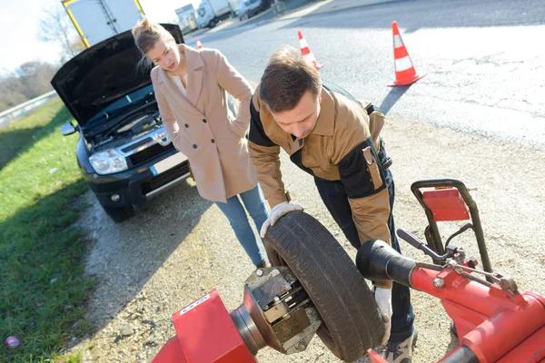 Professional changing wheel by side of road — Stock Photo, Image