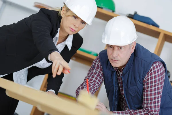 Female architect and construction worker looking at scale model — Stock Photo, Image