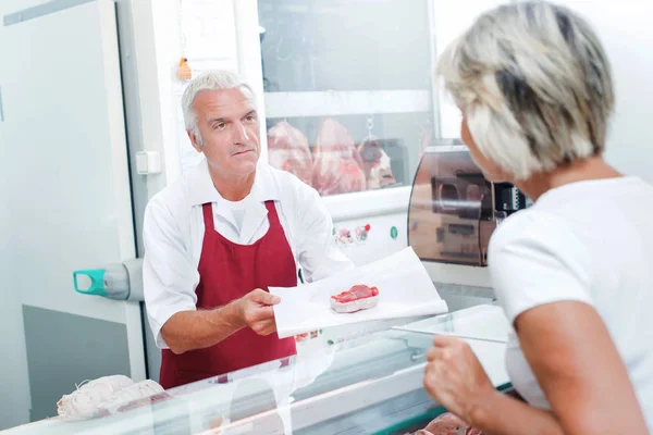 Carniceiro servindo um de seus clientes — Fotografia de Stock