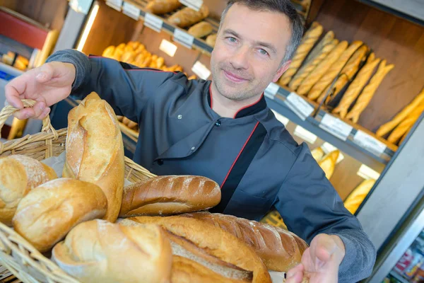 Bäcker hält Korb mit Broten — Stockfoto