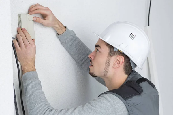Homem ajustando o controlador de termostato à parede — Fotografia de Stock
