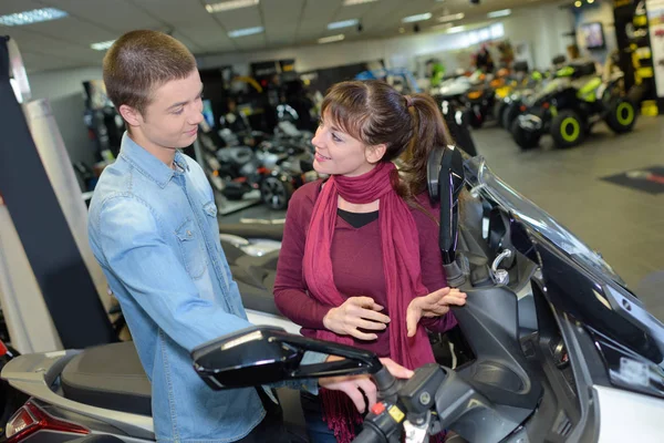 Woman looking at scooter in showroom — Stock Photo, Image