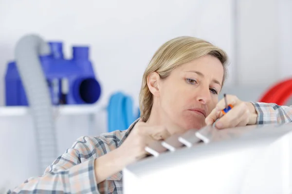 Blonde Heimwerkerin putzt Lüftungsanlage — Stockfoto