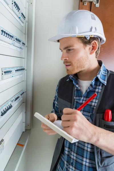 Jeune électricien travaillant sur panneau électrique — Photo