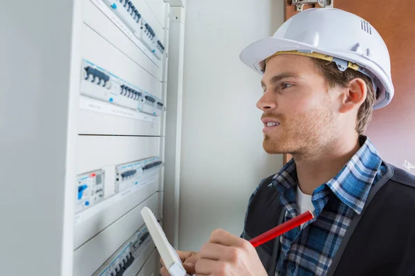 Unga elektriker arbetar med elpanel — Stockfoto