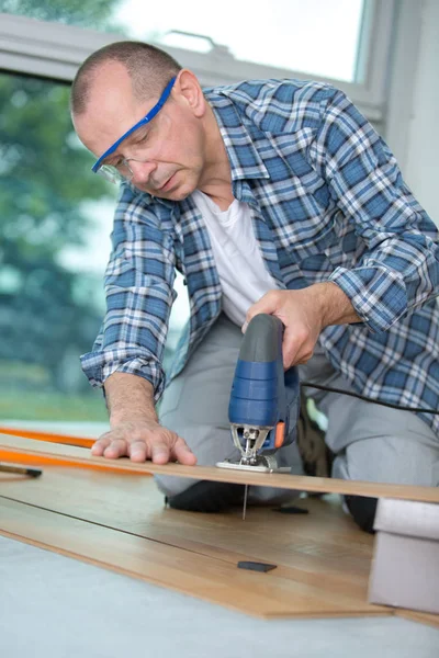 Timmerman snijden gelaagde planken voor gelaagd parket met behulp van bandzagen — Stockfoto
