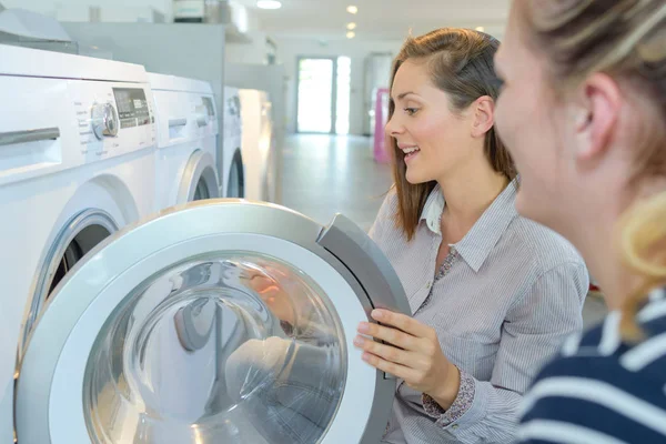 Женщины смотрят стиральные машины в магазине — стоковое фото