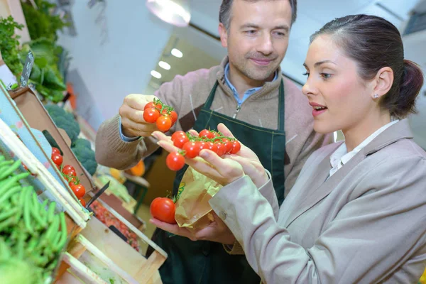 Smiling woman choosing different fruits at farm food store display — Stock Photo, Image