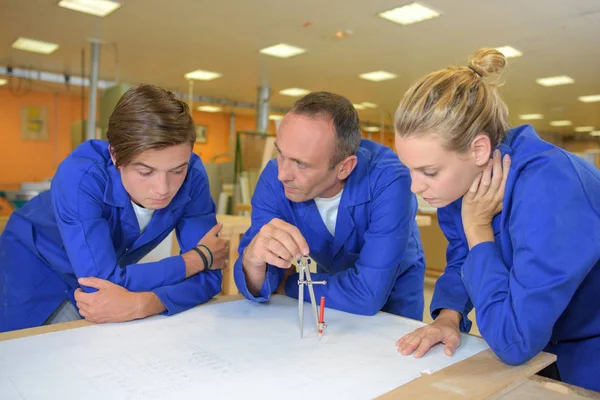 Tutor usando brújula con dos aprendices —  Fotos de Stock