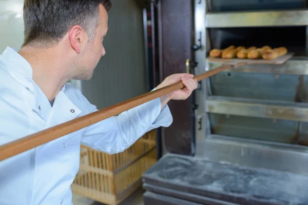 Baker verwijderen brood uit de oven — Stockfoto