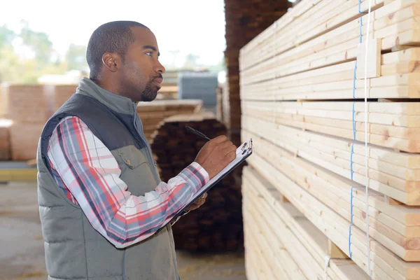 Homem observando referência de madeira na área de transferência — Fotografia de Stock