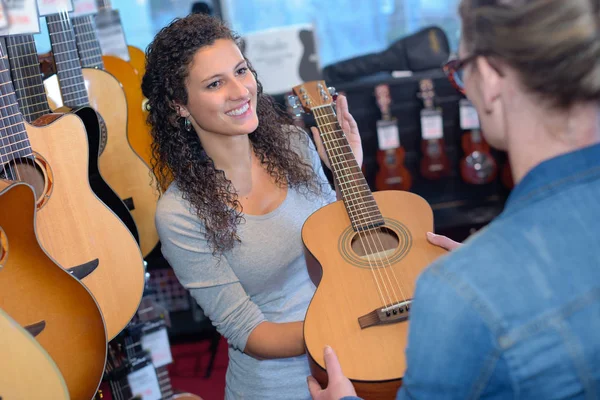 Vrouw passeren gitaar aan klant — Stockfoto