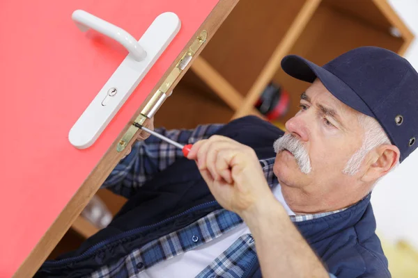 Senior homme réparer serrure de porte avec tournevis — Photo