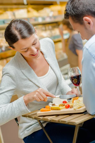 Coppia che mangia, signora che taglia formaggio — Foto Stock