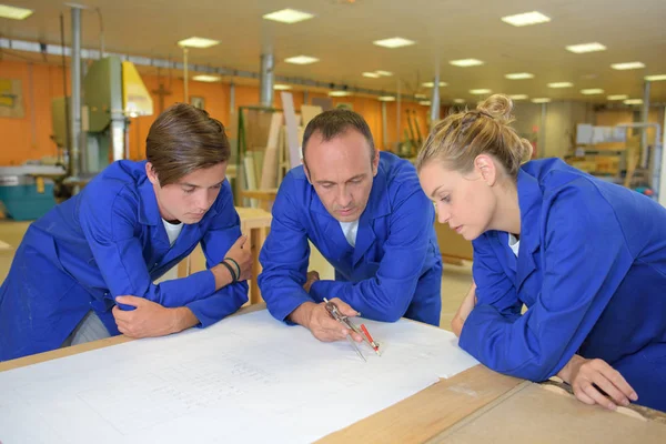 Arbeiter am Tisch betrachten Papierkram — Stockfoto