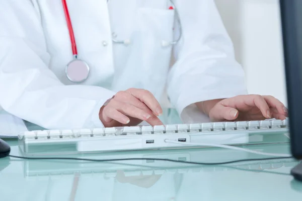 Female doctor sitting at the table and typing on computer — Stock Photo, Image