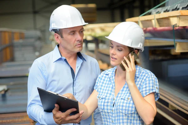 Man and woman in warehouse looking at clipboard — Stock Photo, Image