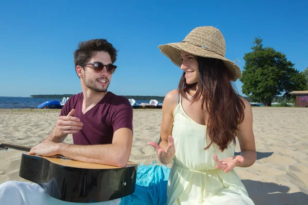 Young man with his guitar and girlfriend on the beach — Stock Photo, Image