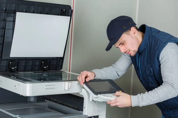 Jovem técnico do sexo masculino reparando máquina de impressora fotocopiadora digital — Fotografia de Stock