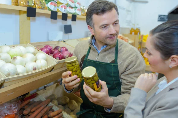 Smiling woman choosing different fruits at farm food store display — Stock Photo, Image