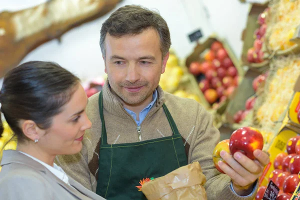 Greengrocer servindo maçã para o cliente — Fotografia de Stock