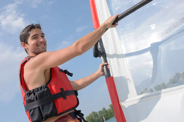 Apuesto joven windsurfista en el agua Imagen de stock