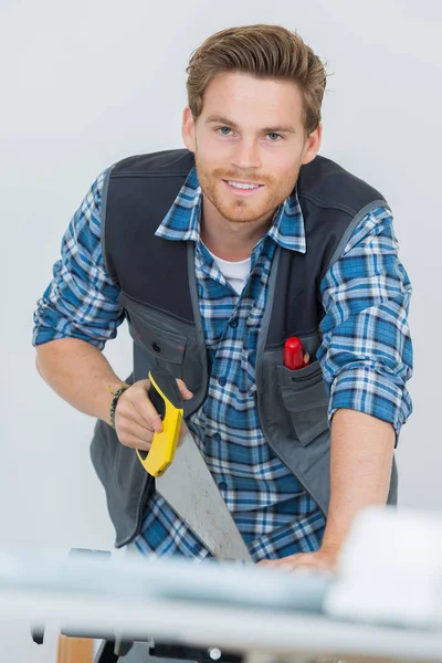 Retrato del carpintero que trabaja con una sierra en obra — Foto de Stock