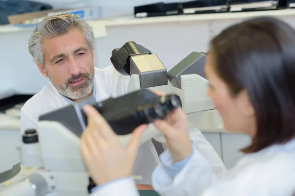 Labb arbetstagaren hålla mikroskopet och prata med kollega — Stockfoto