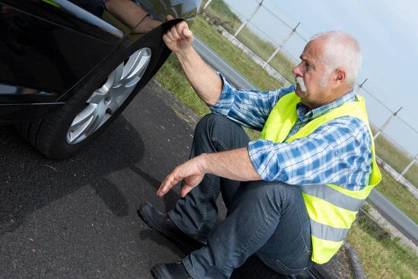 Cesareti kırılmış emekli adam araba lastik değiştirilemiyor — Stok fotoğraf