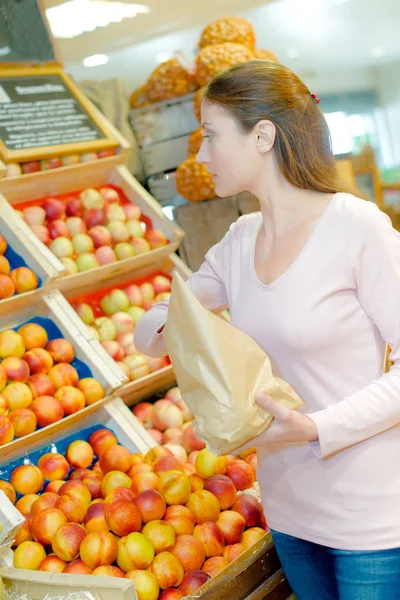 Lady comprando nectarinas, sosteniendo una bolsa de papel — Foto de Stock
