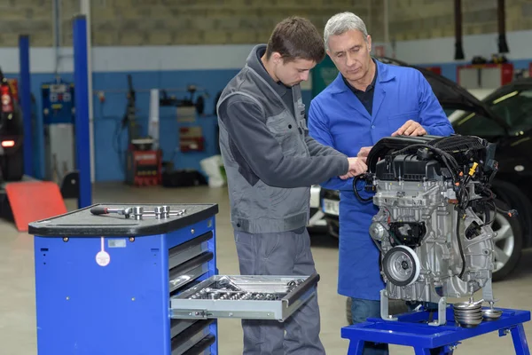 Student met instructeur die een auto repareert tijdens het leerlingwezen — Stockfoto