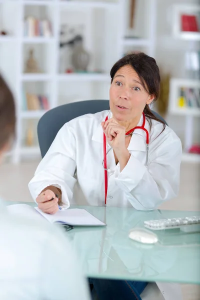 Grazioso medico di mezza età parlando con il suo paziente — Foto Stock