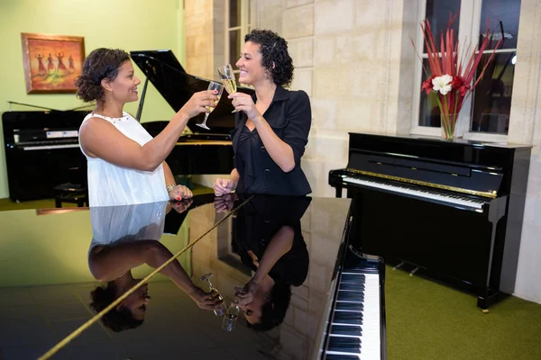 Donna brindare con champagne accanto ai pianoforti — Foto Stock