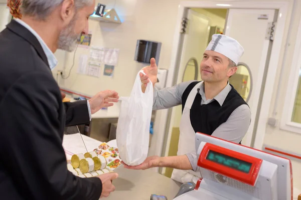 ビニール袋内の顧客に食材を渡す店主 — ストック写真